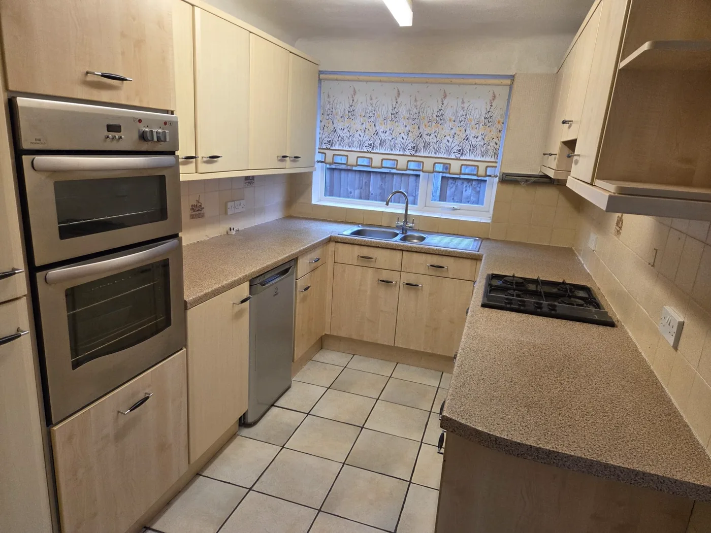 The original compact cream kitchen, with a built-in double oven, hob and tiled floor.