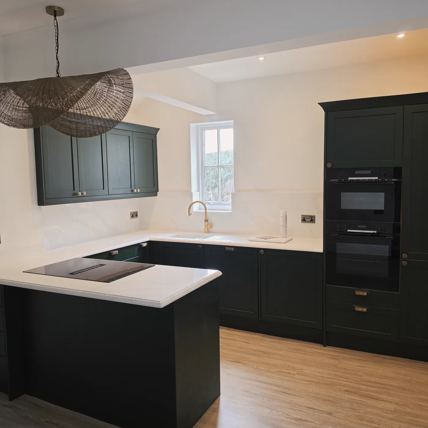 The finished kitchen in deep green, with a pendant light over the full layout.