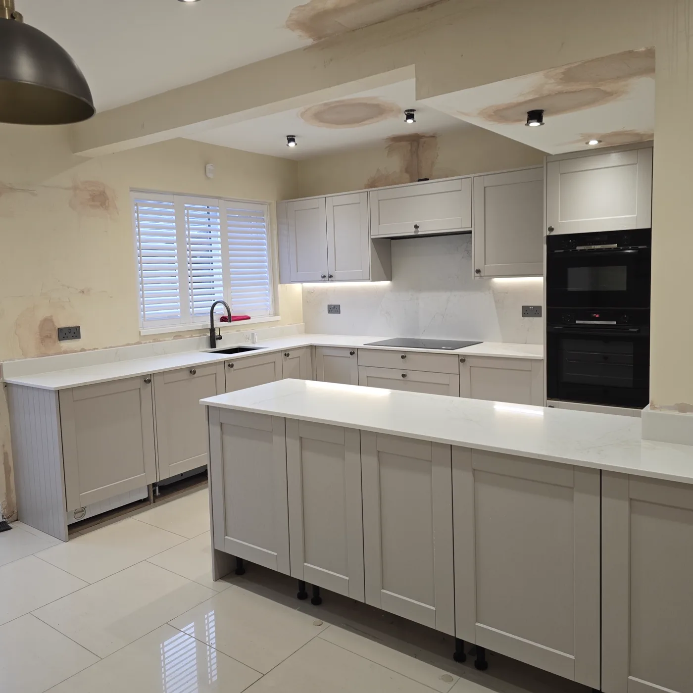 The finished kitchen from the sink side, showing the white quartz worktop.