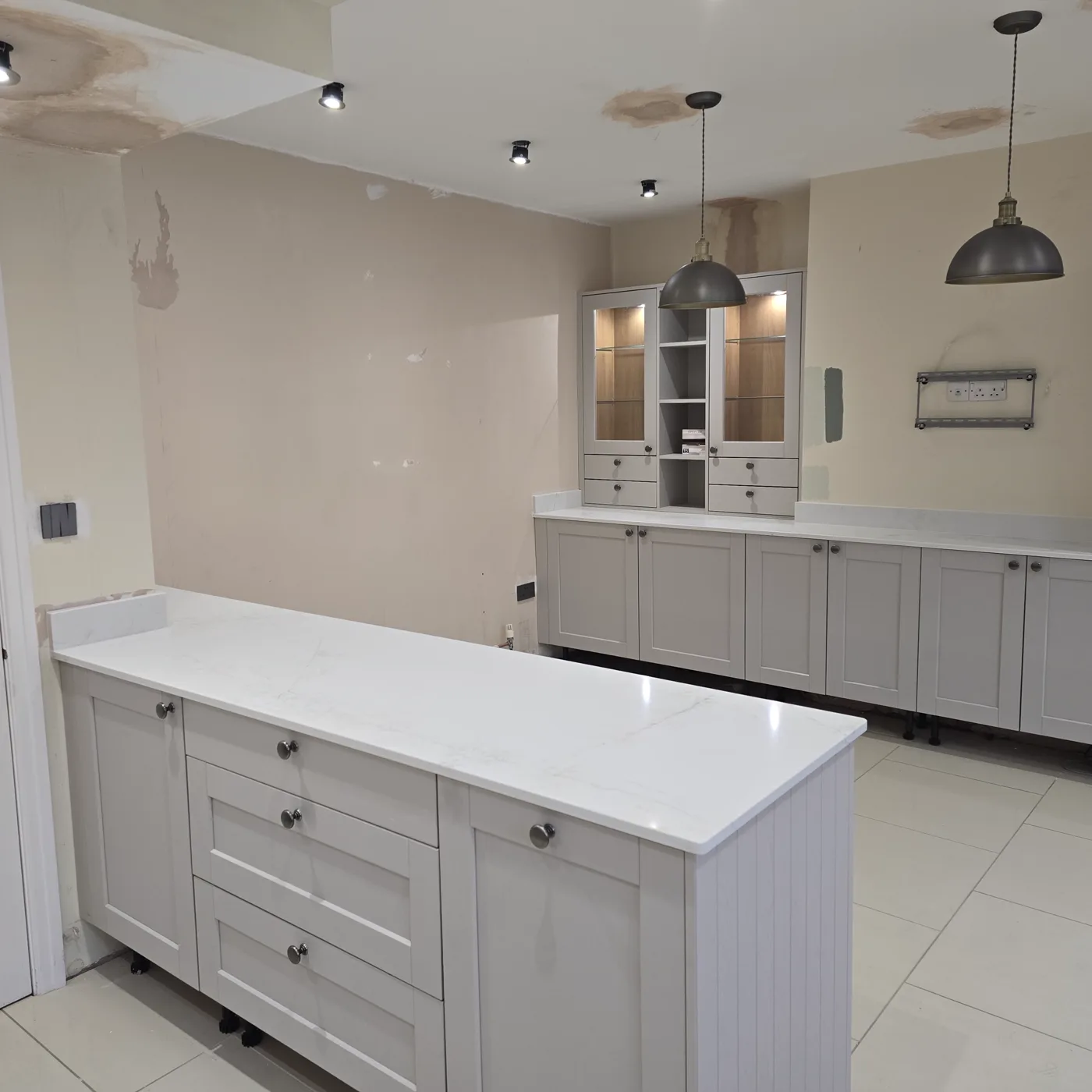 The finished kitchen, with a central island, black built-in oven and under-cabinet lighting.