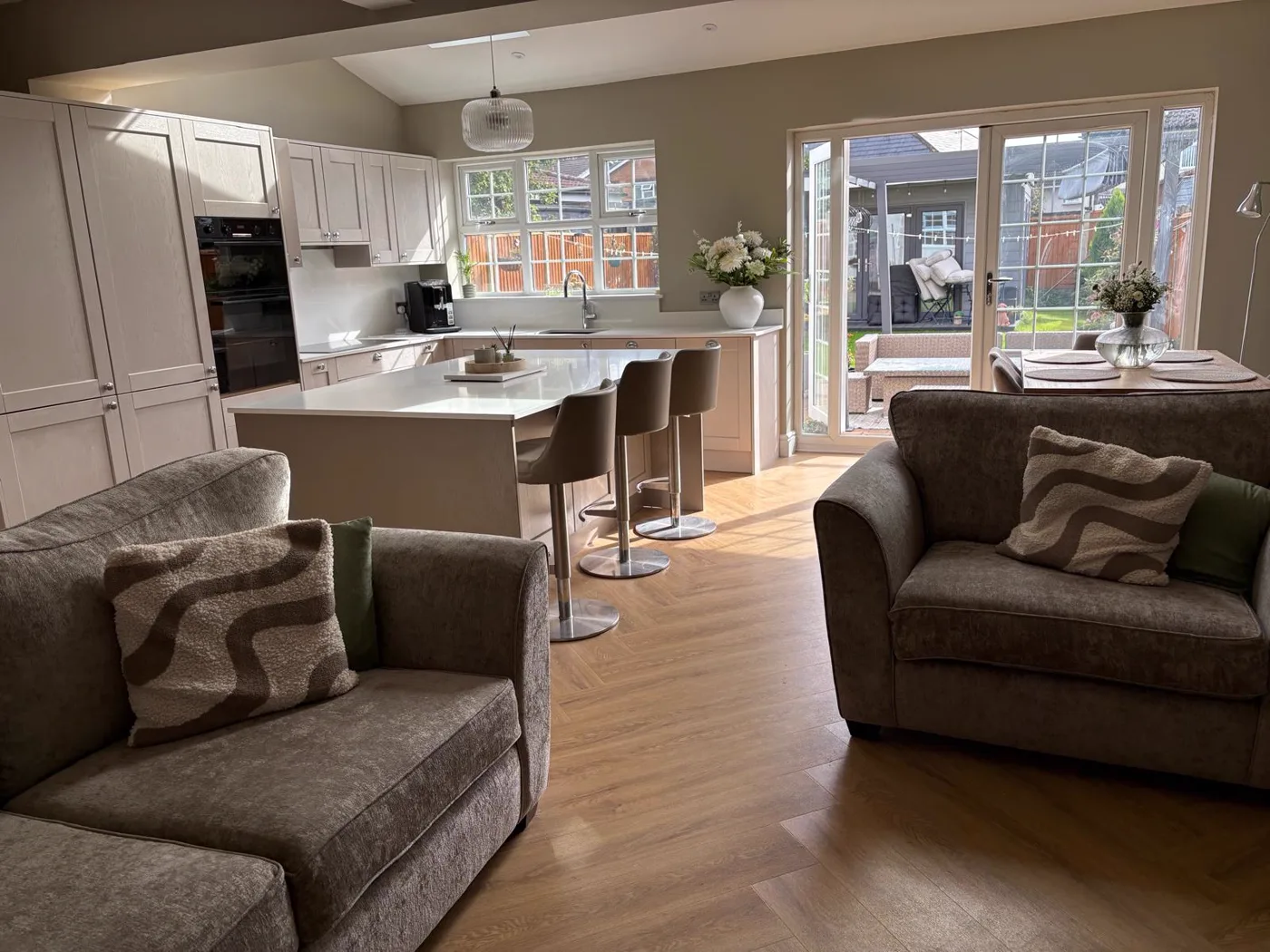 The finished open-plan kitchen with soft grey cabinetry and a central island.